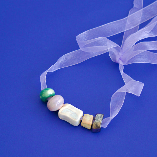 Colier unicat cu charmuri din ceramica de diferite culori pastel pe snur din organza roz.