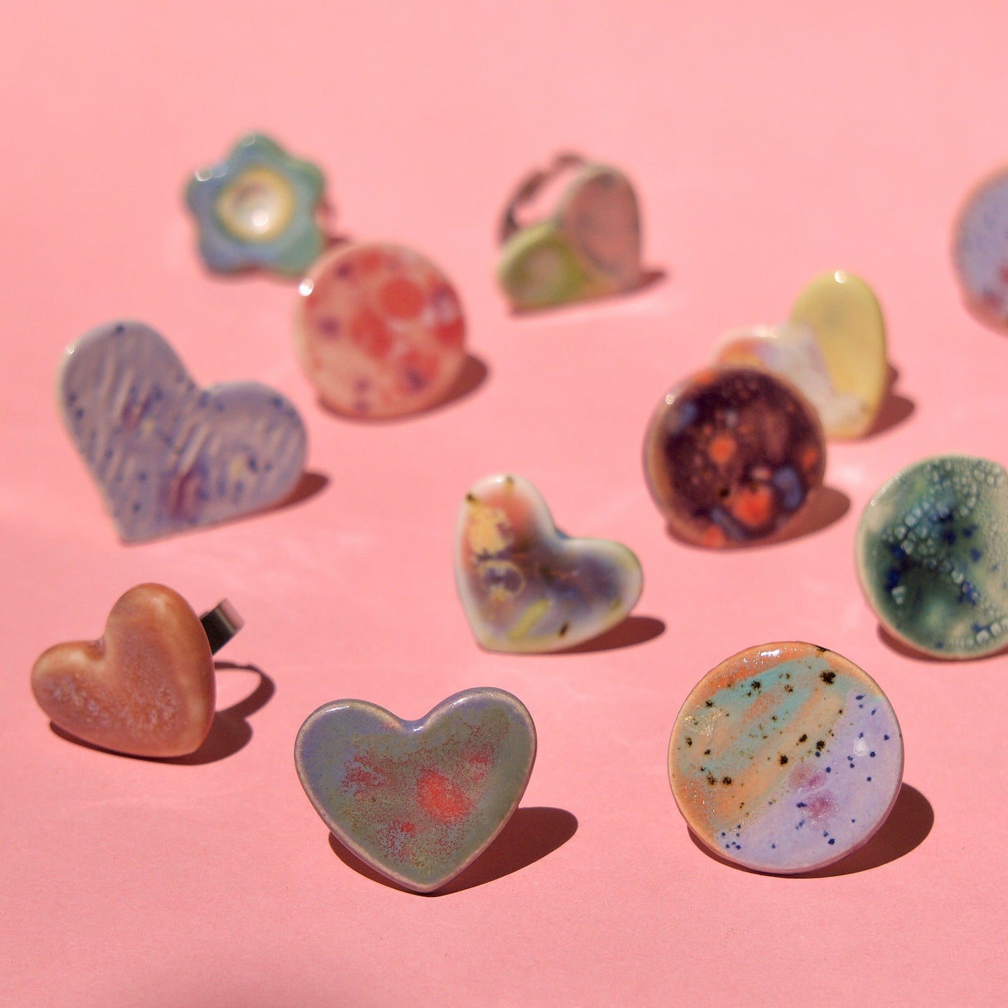 Colecție de inele handmade din porțelan, în forme variate (inimă, cerc, floare), glazurate în nuanțe pastel și montate pe tije din oțel inoxidabil – bijuterii Ecluze Studio