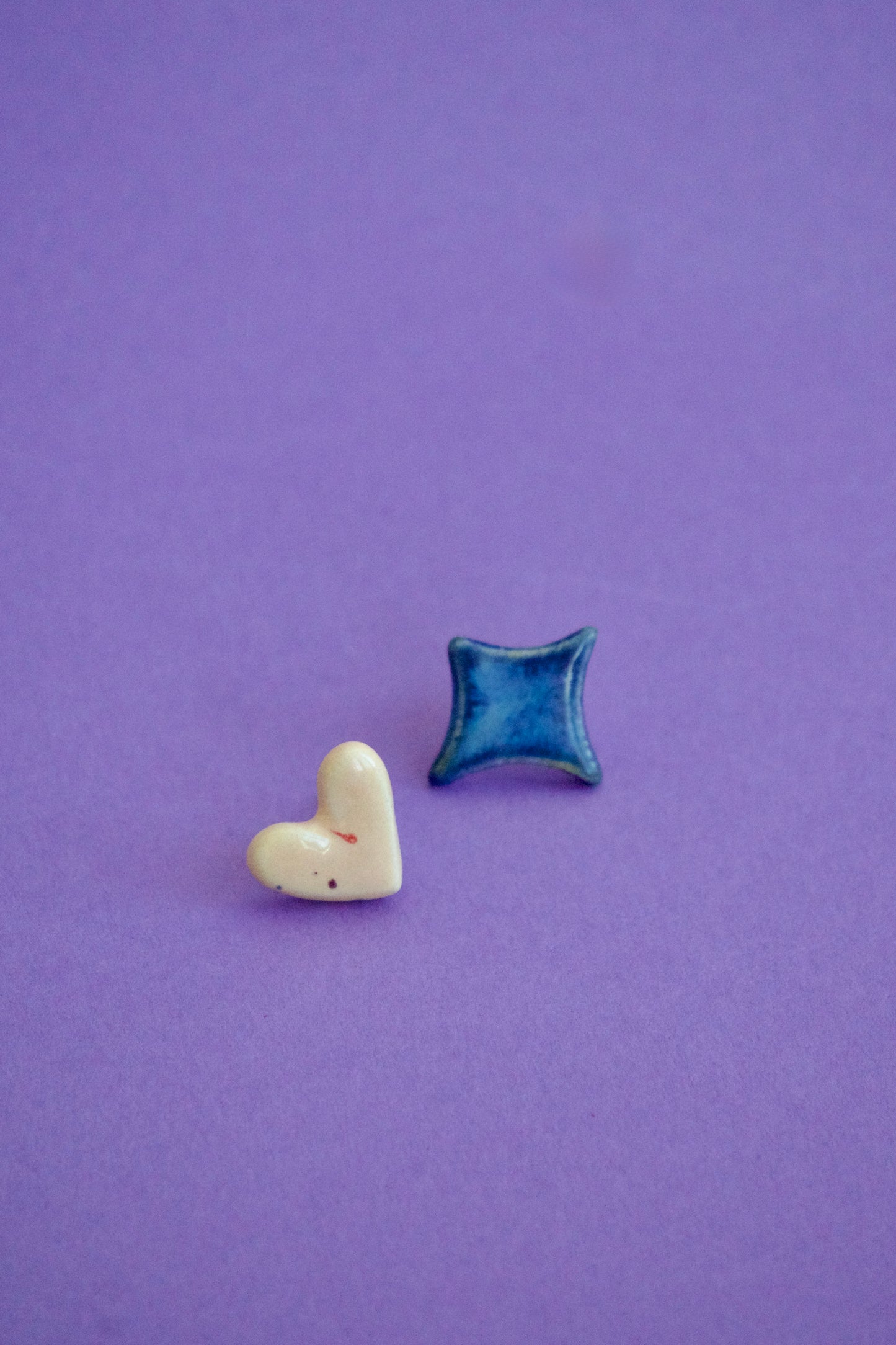 Cercei handmade din ceramică asimetrici – inimă crem și romb albastru lucios, cu tije hipoalergenice.