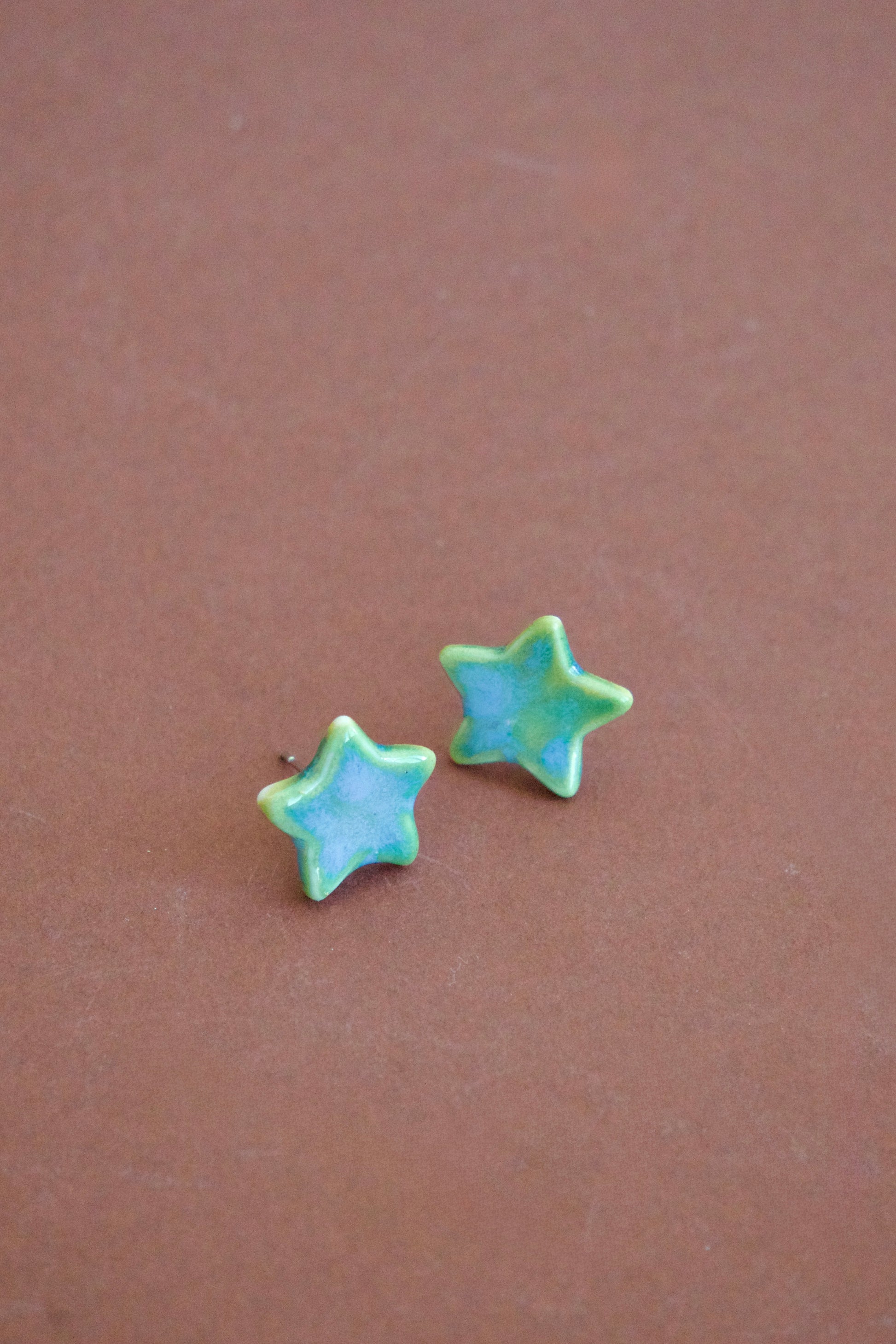 Cercei handmade din porțelan în formă de steluțe verzi cu accente albastre, finisaj lucios, tije hipoalergenice.