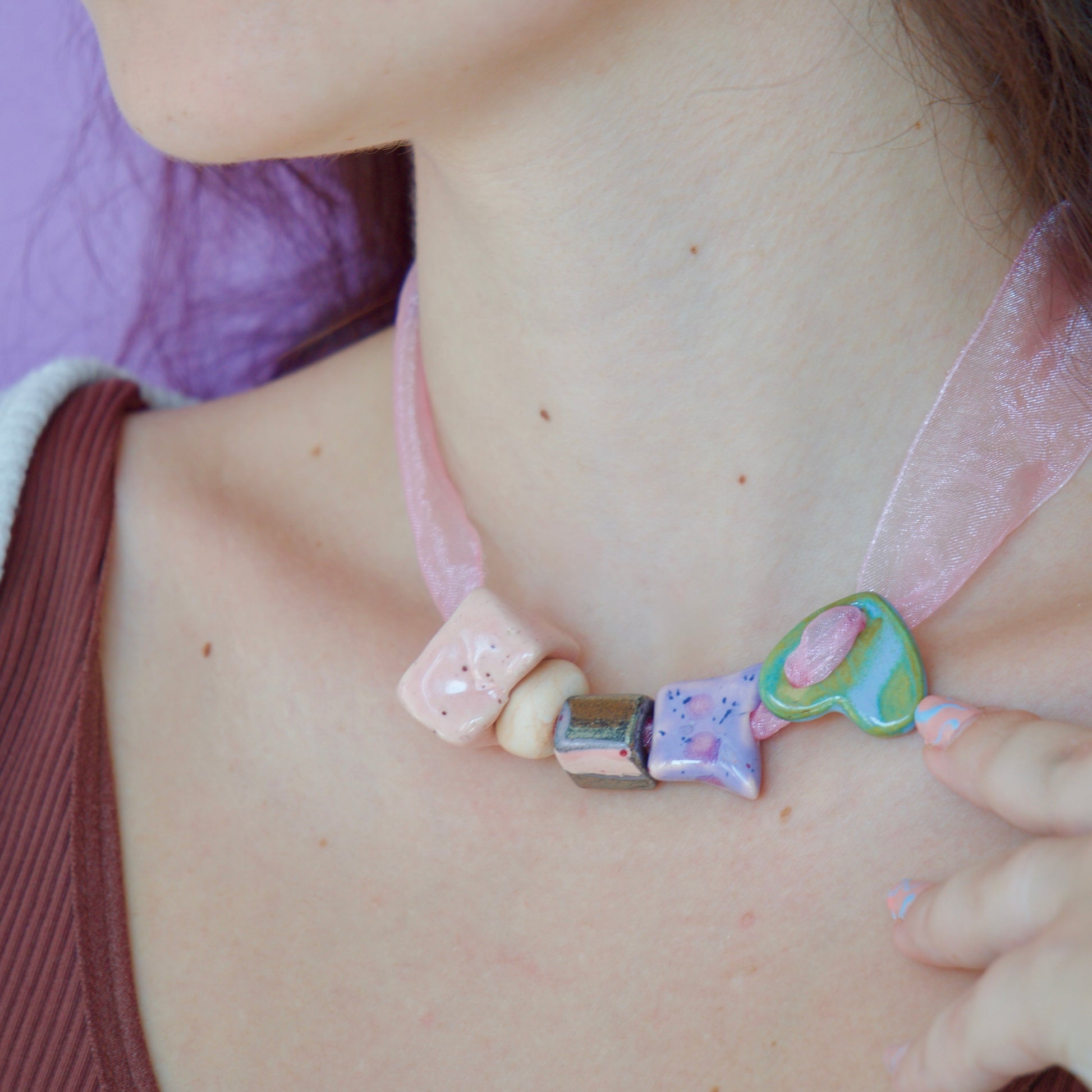 Colier unicat cu 5 charmuri colorate din ceramica de diferite culori (verde, mov, roz, bej, negru) pe snur roz din organza purtat la gat impreuna cu cercei inimioare roz si mov.