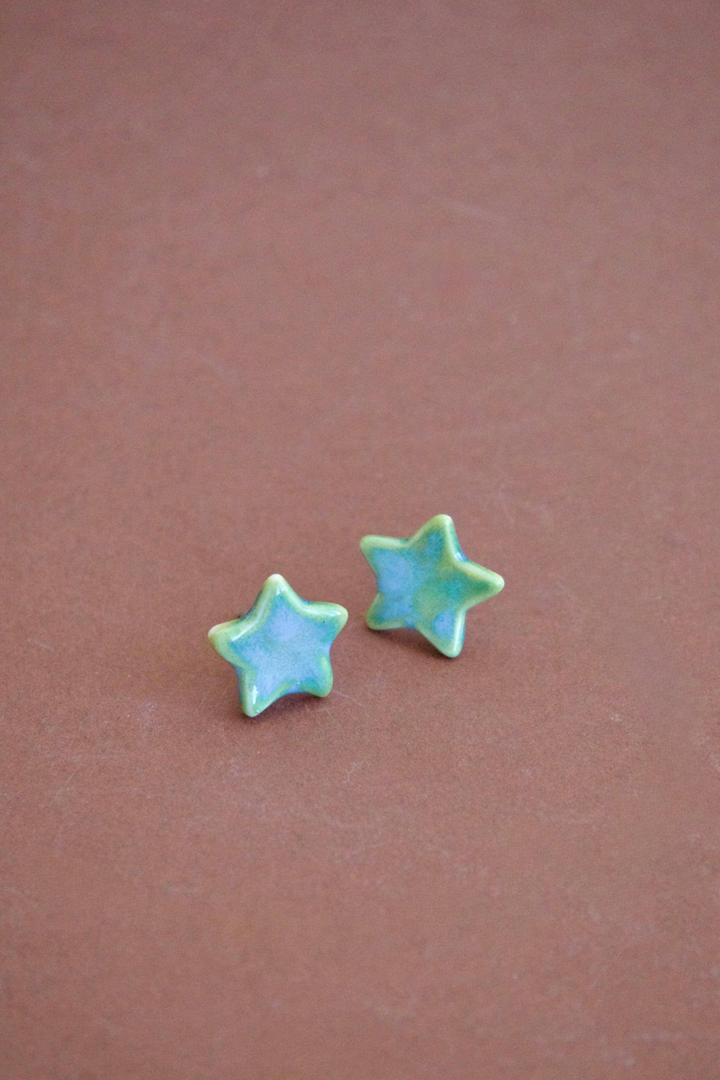 Cercei handmade din porțelan în formă de steluțe verzi cu accente albastre, finisaj lucios, tije hipoalergenice.