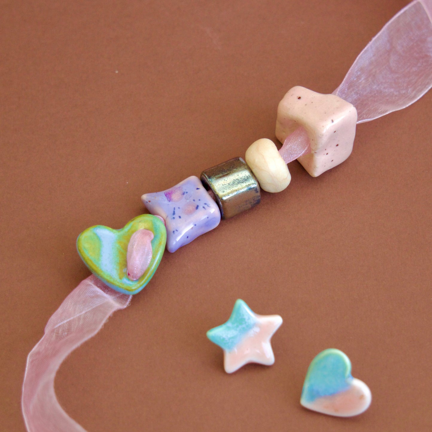 Colier unicat cu 5 charmuri colorate din ceramica de diferite culori (verde, mov, roz, bej, negru) pe snur roz din organza.