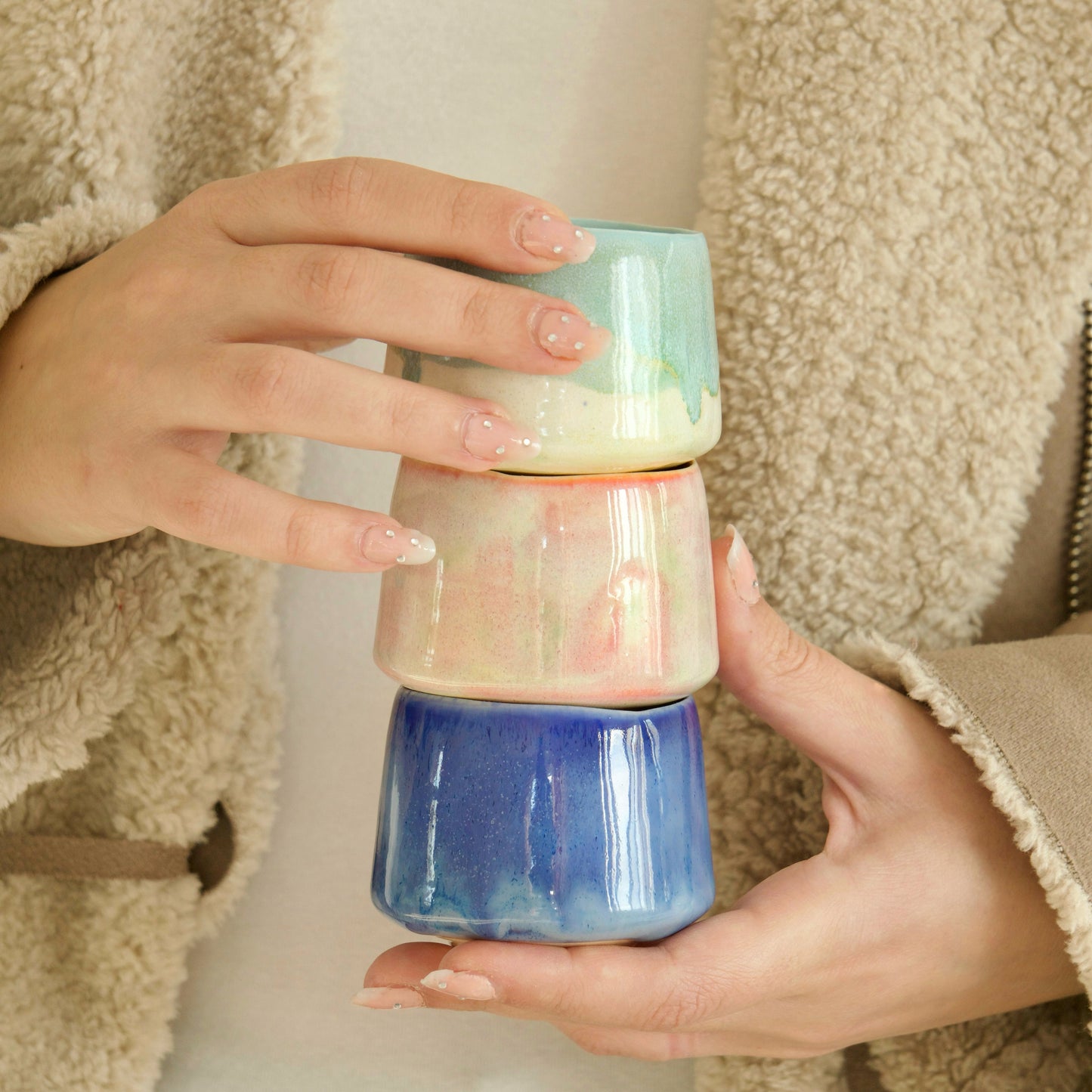 Persoană ținând 3 cani de espresso din semi-porțelan, glazurate în nuanțe pastelate – Ecluze Studio.