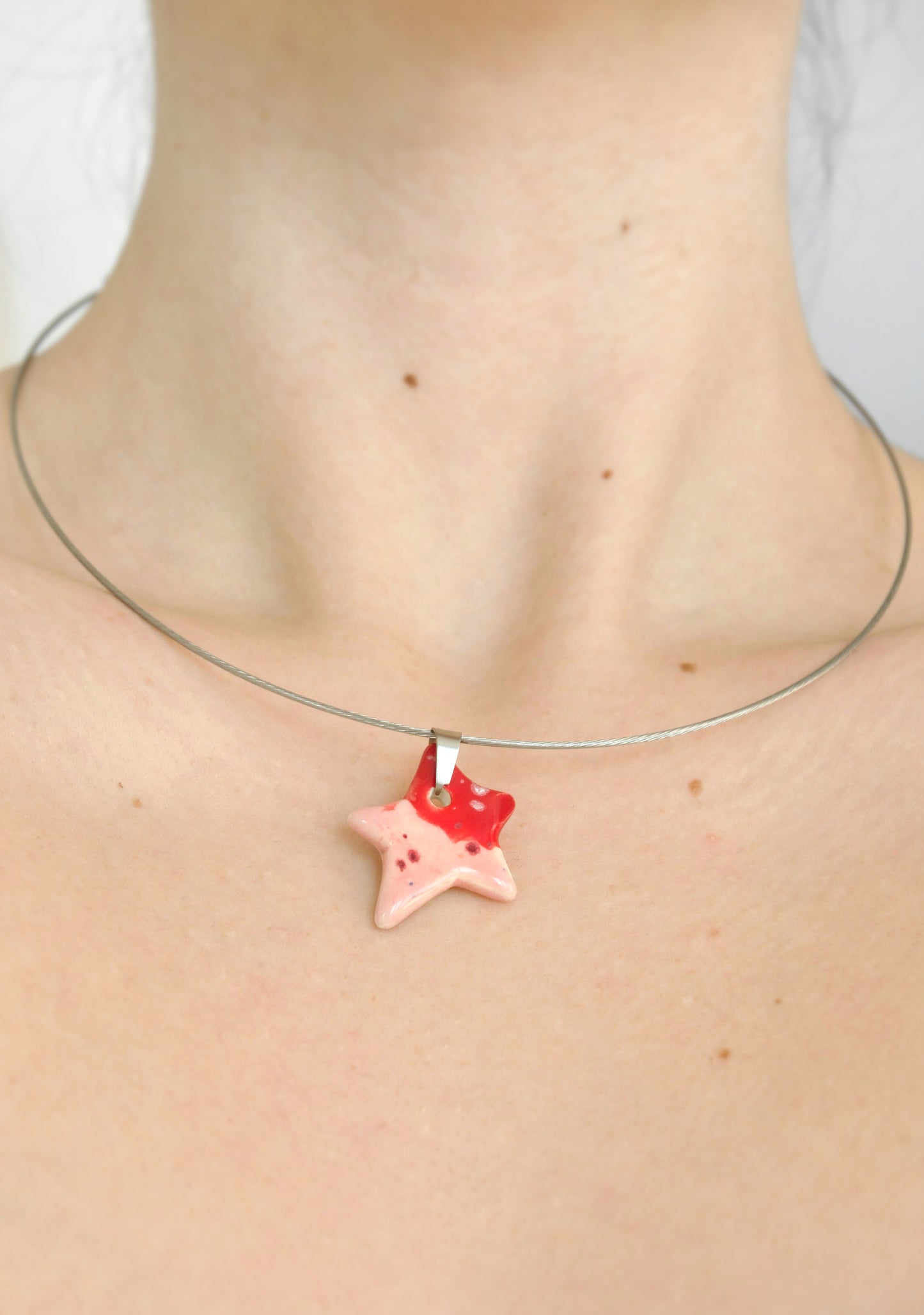 Colier handmade cu pandantiv ceramic în formă de stea purtat la gat, montat pe choker din oțel inoxidabil hipoalergenic.