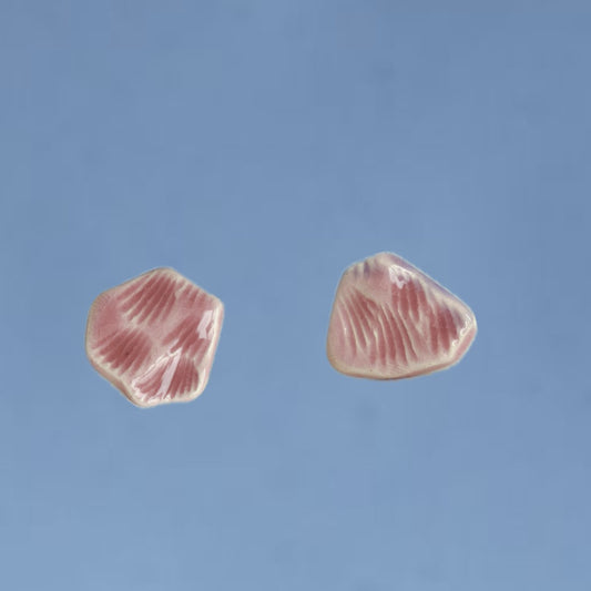 Cercei handmade din porțelan cu formă organică, roz pastel pe fundal albastru.