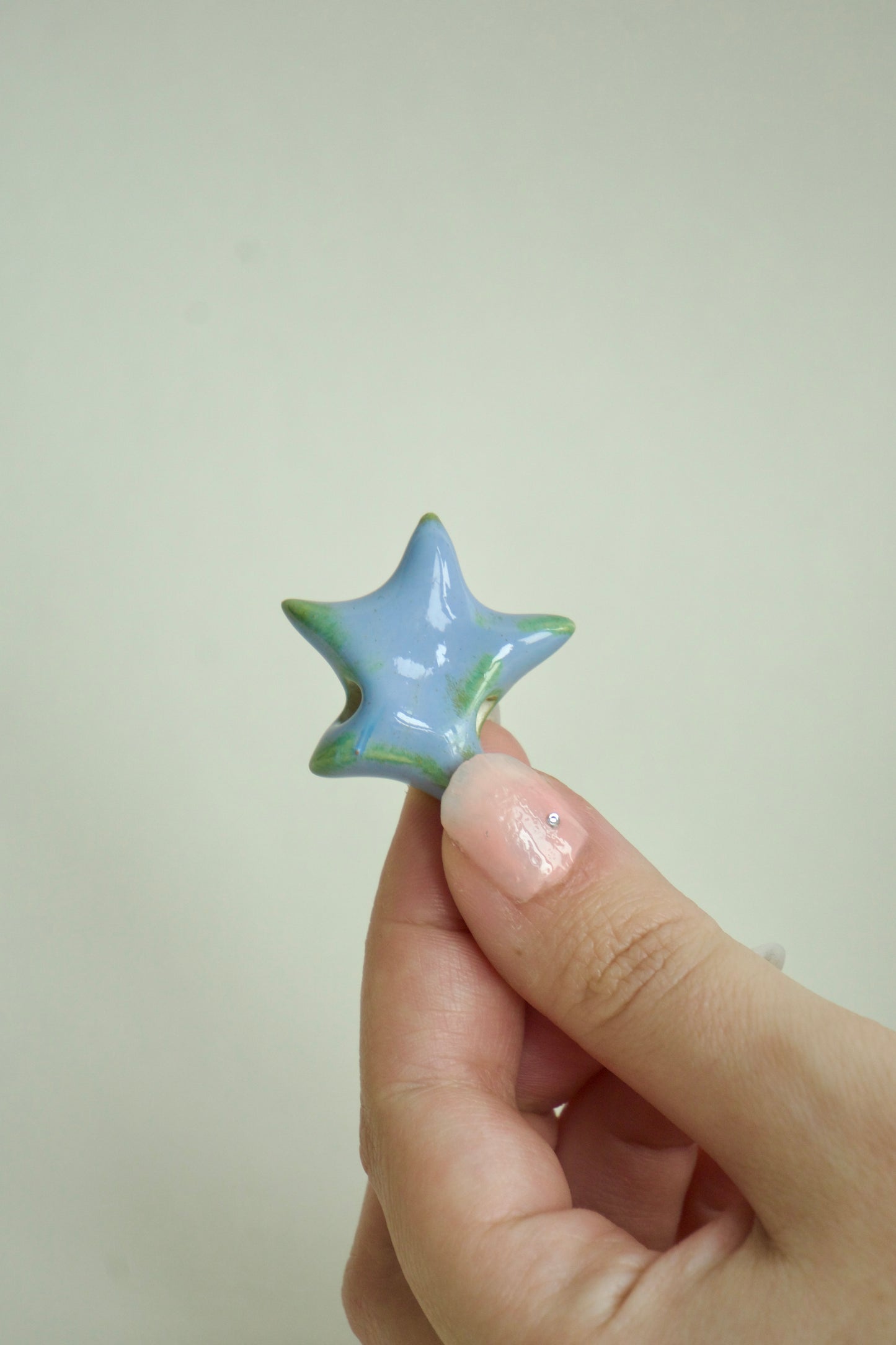 Charm ceramic realizat manual, formă de stea, albastru cu reflexe verzi, ideal pentru coliere personalizate și bijuterii unicat.