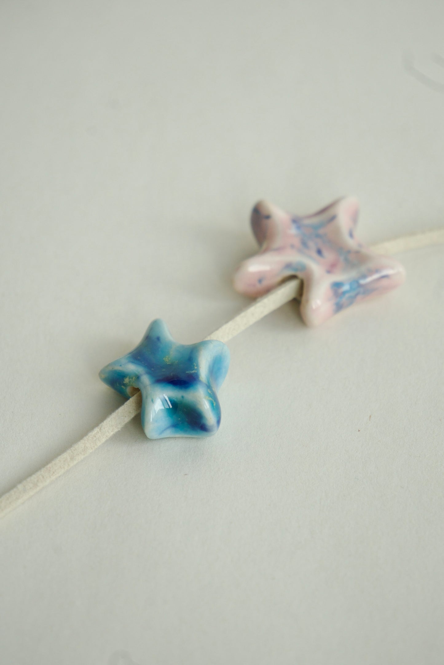 Set de charmuri ceramice în formă de stea, realizate manual, în culori variate: albastru, roz, verde și roșu, prezentate pe fundal alb.