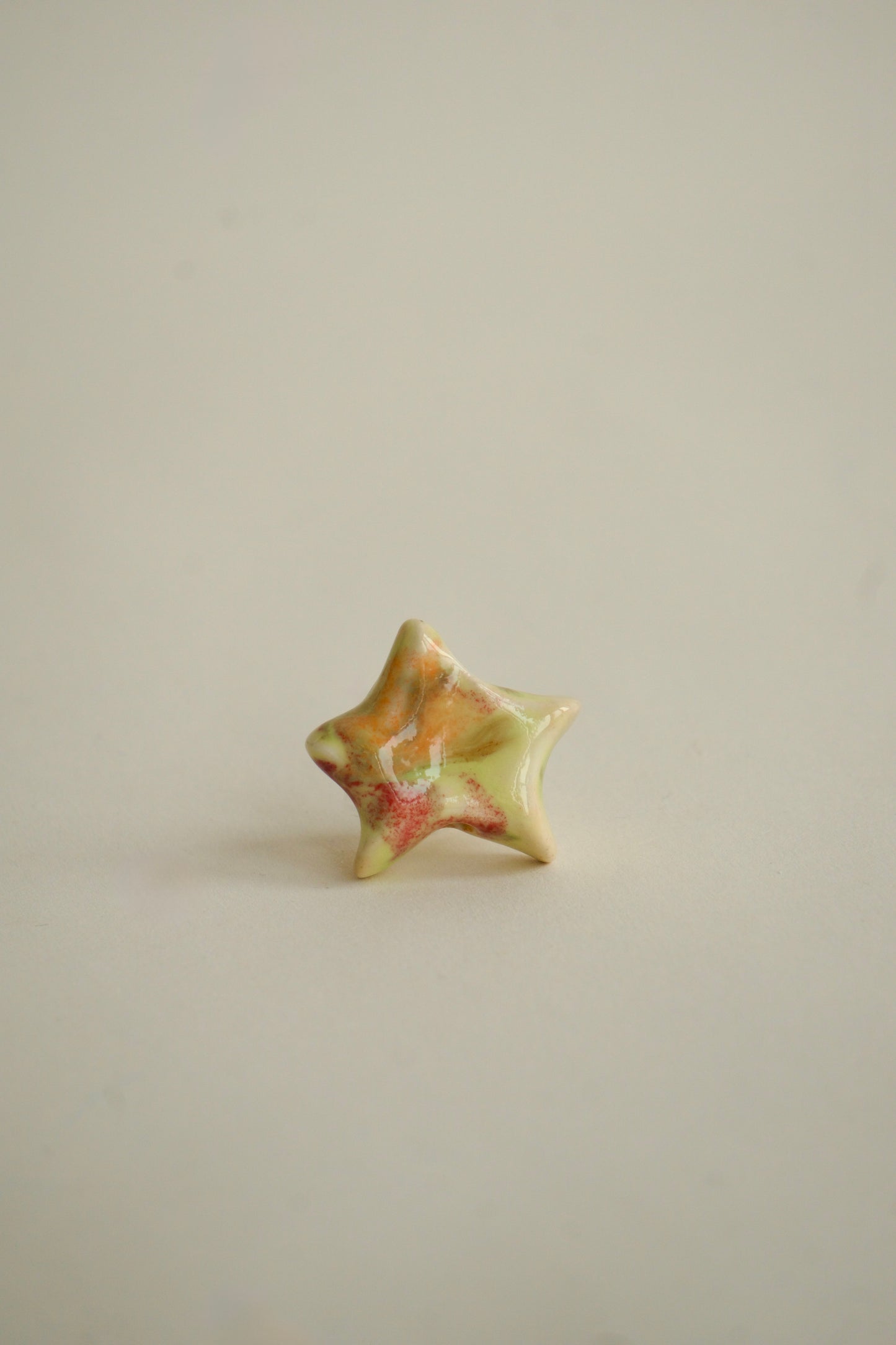 Charm handmade în formă de steluță din ceramică, nuanțe pastel multicolore – roz, galben și verde, finisaj lucios, design unicat.