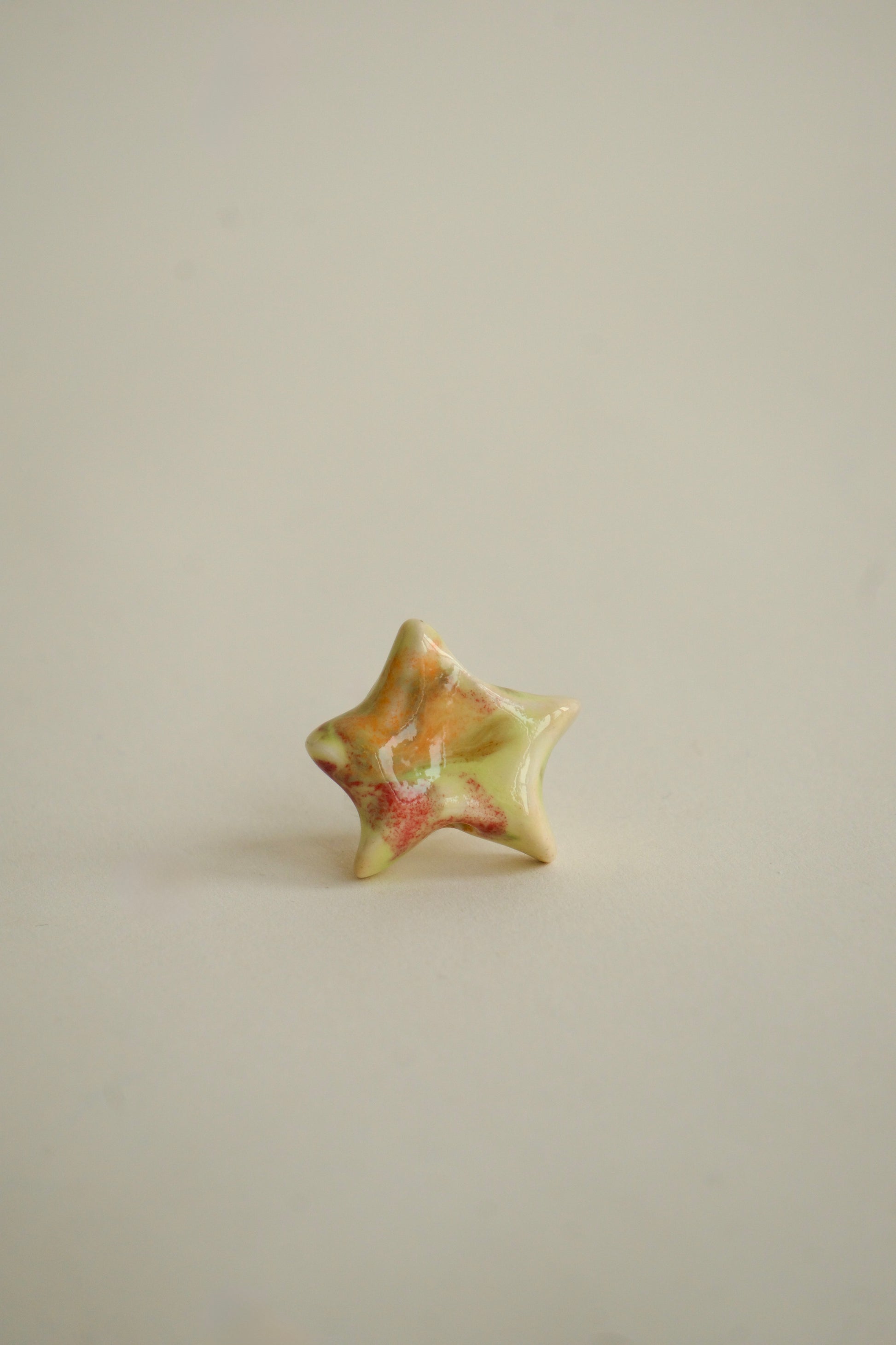 Charm handmade în formă de steluță din ceramică, nuanțe pastel multicolore – roz, galben și verde, finisaj lucios, design unicat.