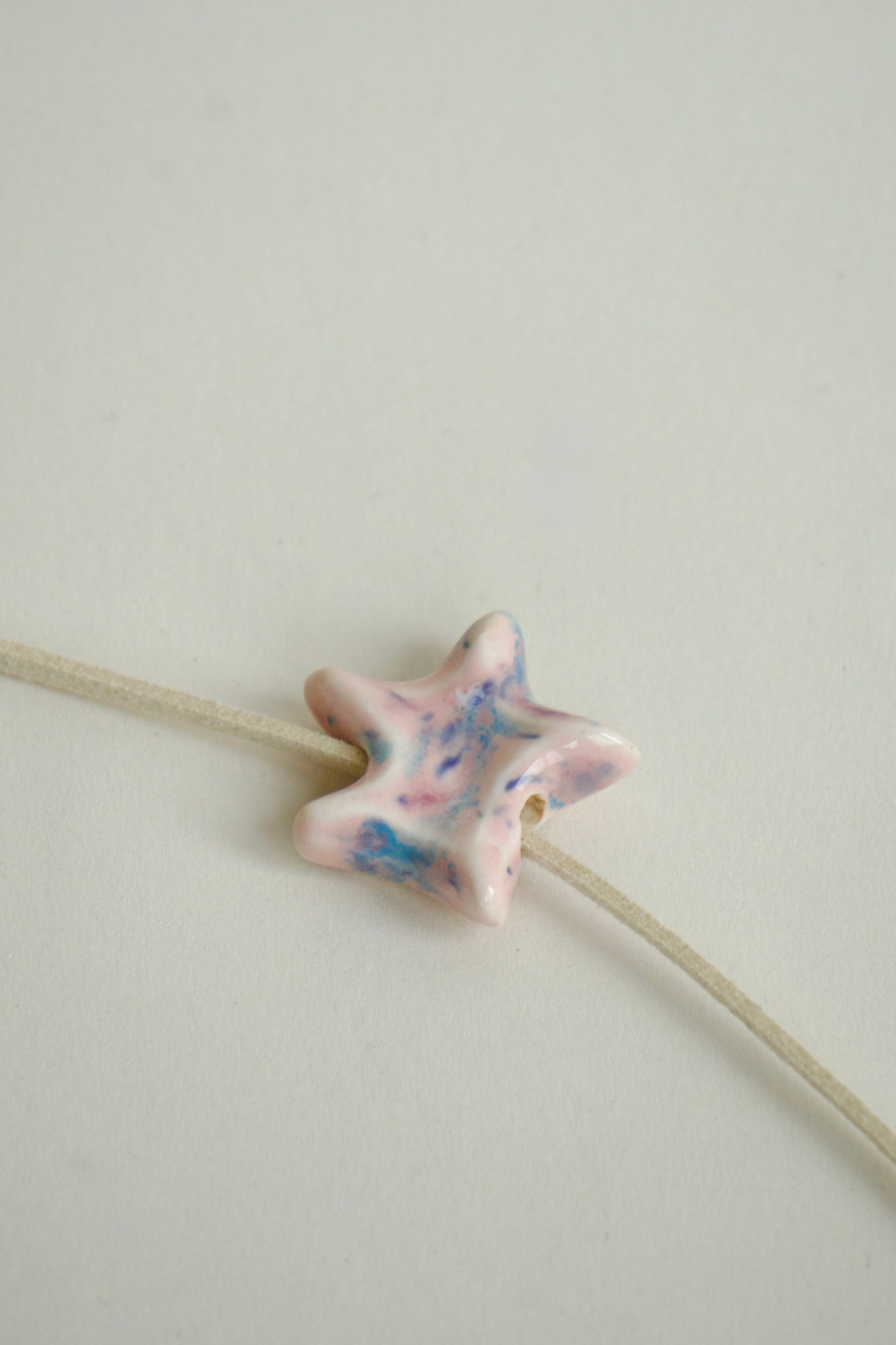 Charm handmade steluță din ceramică, roz pastel și accente albastre, fotografiat din alt unghi, produs unicat.
