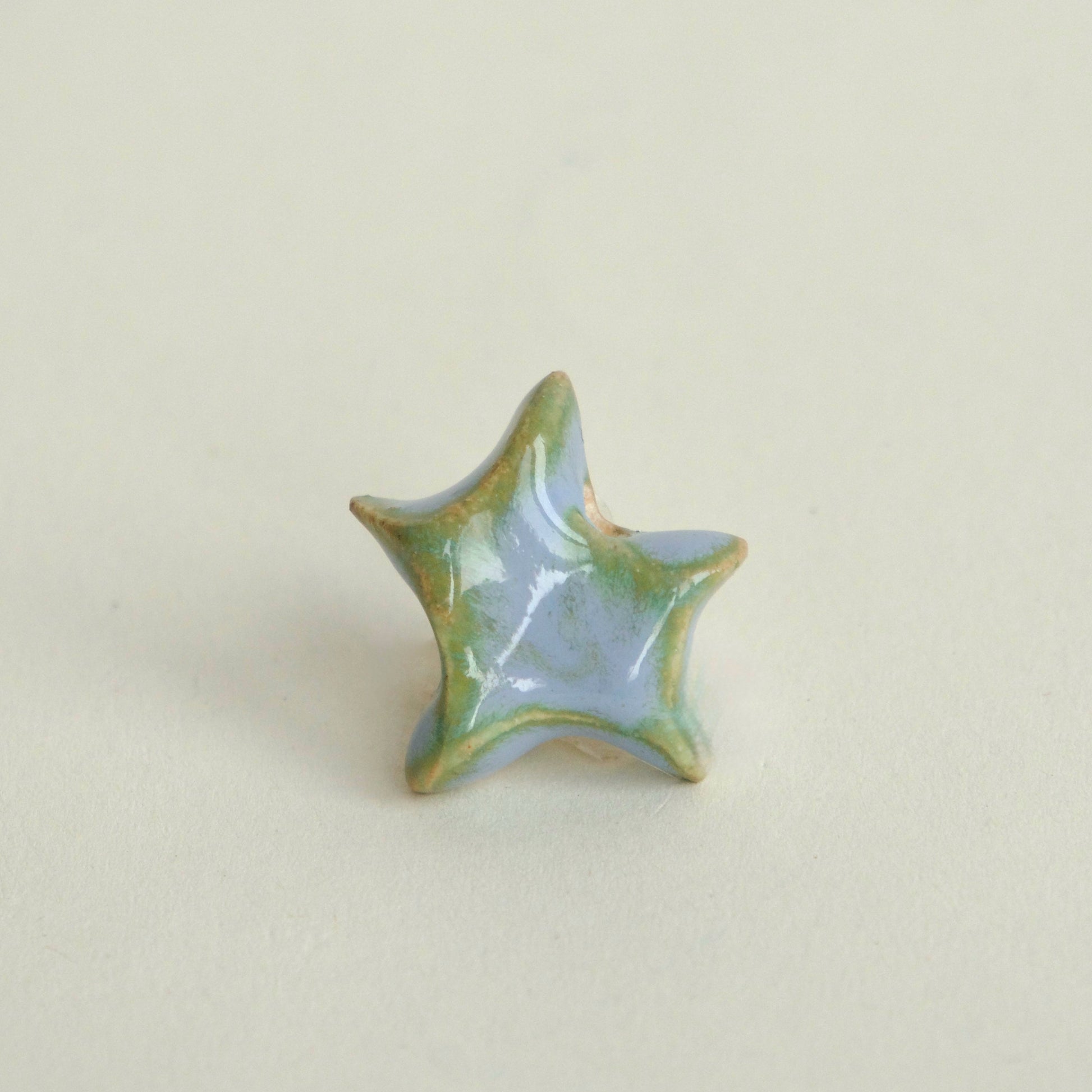 Charm handmade din ceramică în formă de stea albastru cu accente verzi, cu șnur suede bej, ideal pentru coliere personalizate.