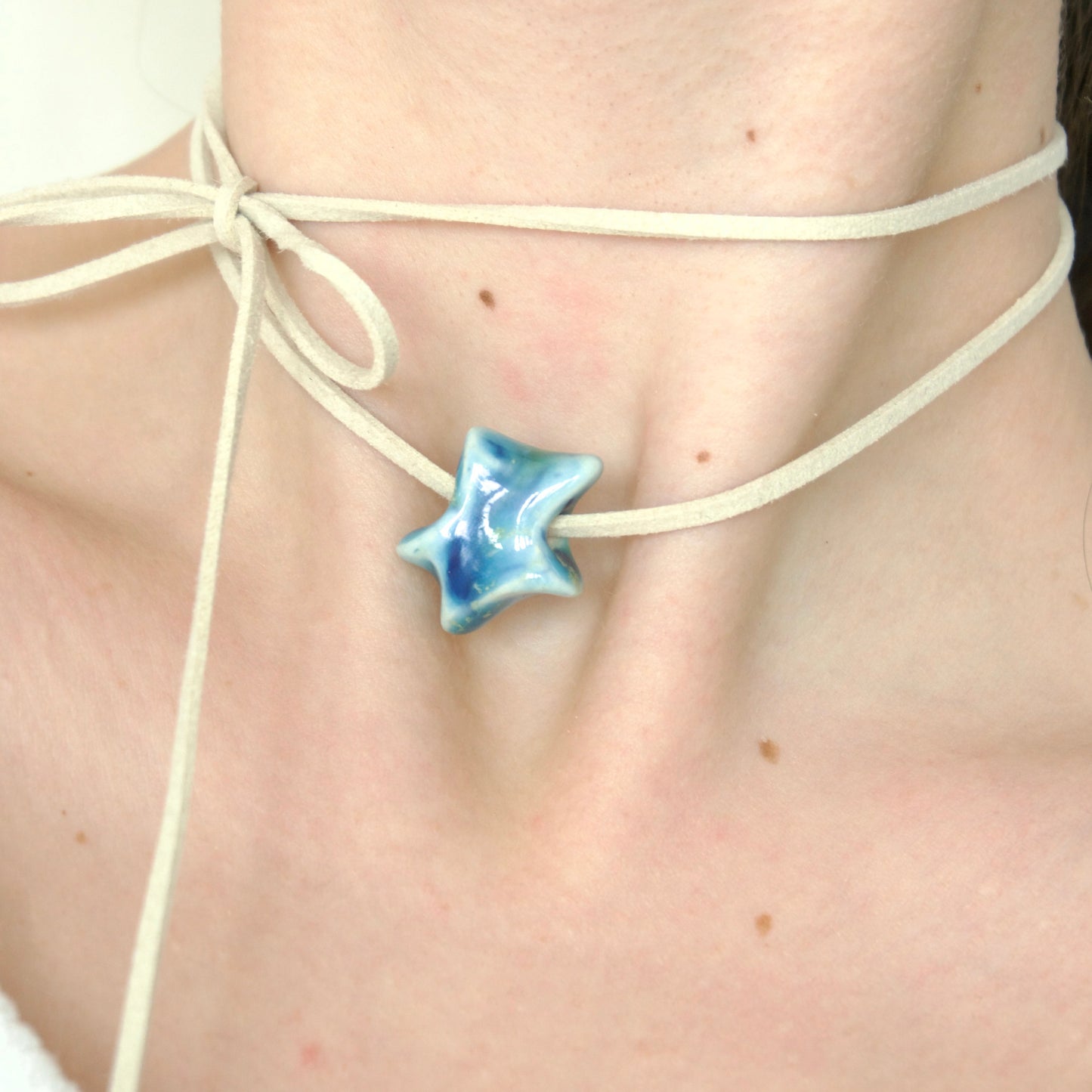 Colier cu pandantiv stea albastru unicat realizat manual din ceramica si prins pe snur suede bej purtat la gat -bijuterii ecluze studio.