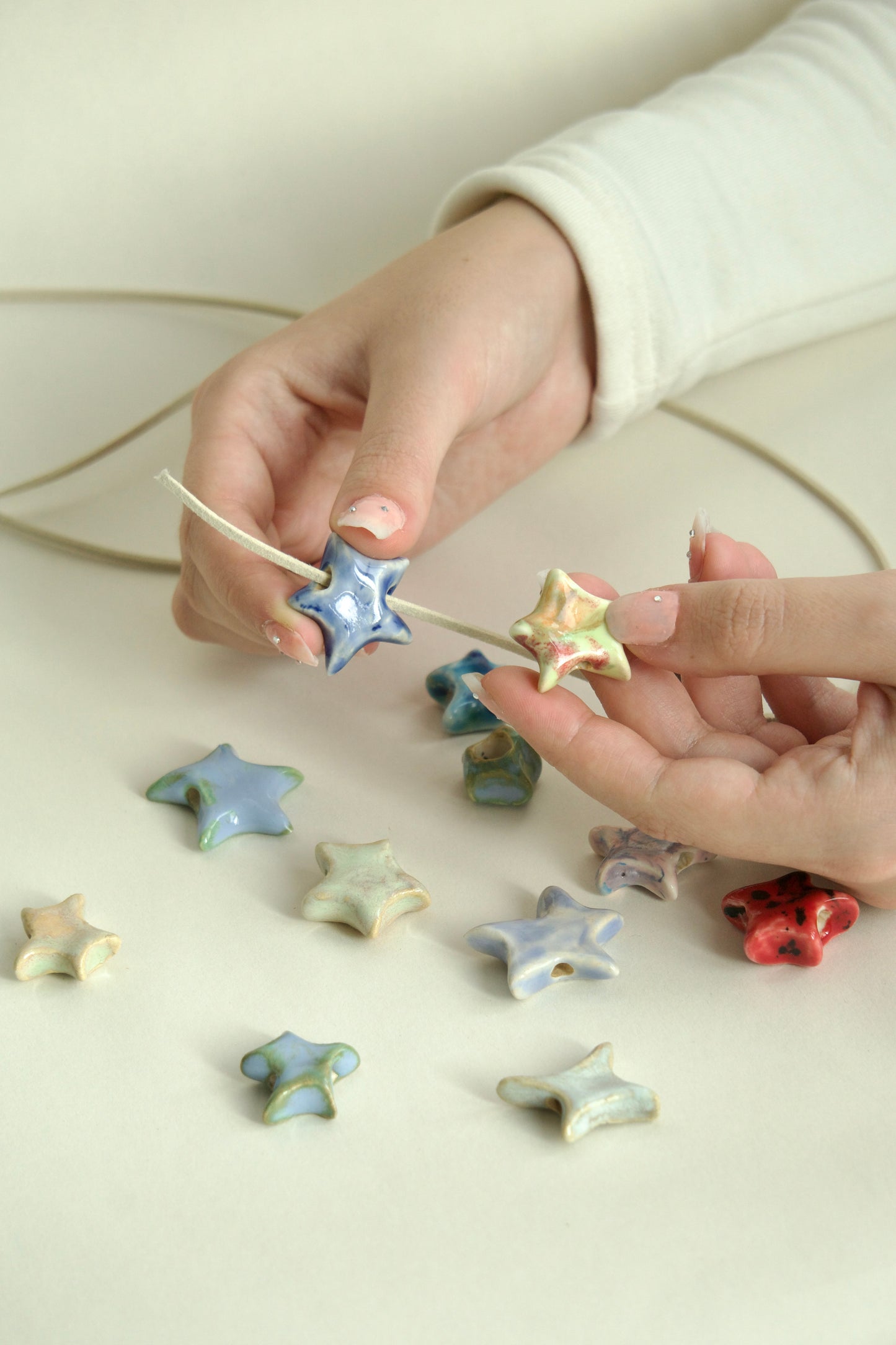 Charmuri handmade din ceramică în formă de stea cu șnur suede bej, ideale pentru coliere personalizate.