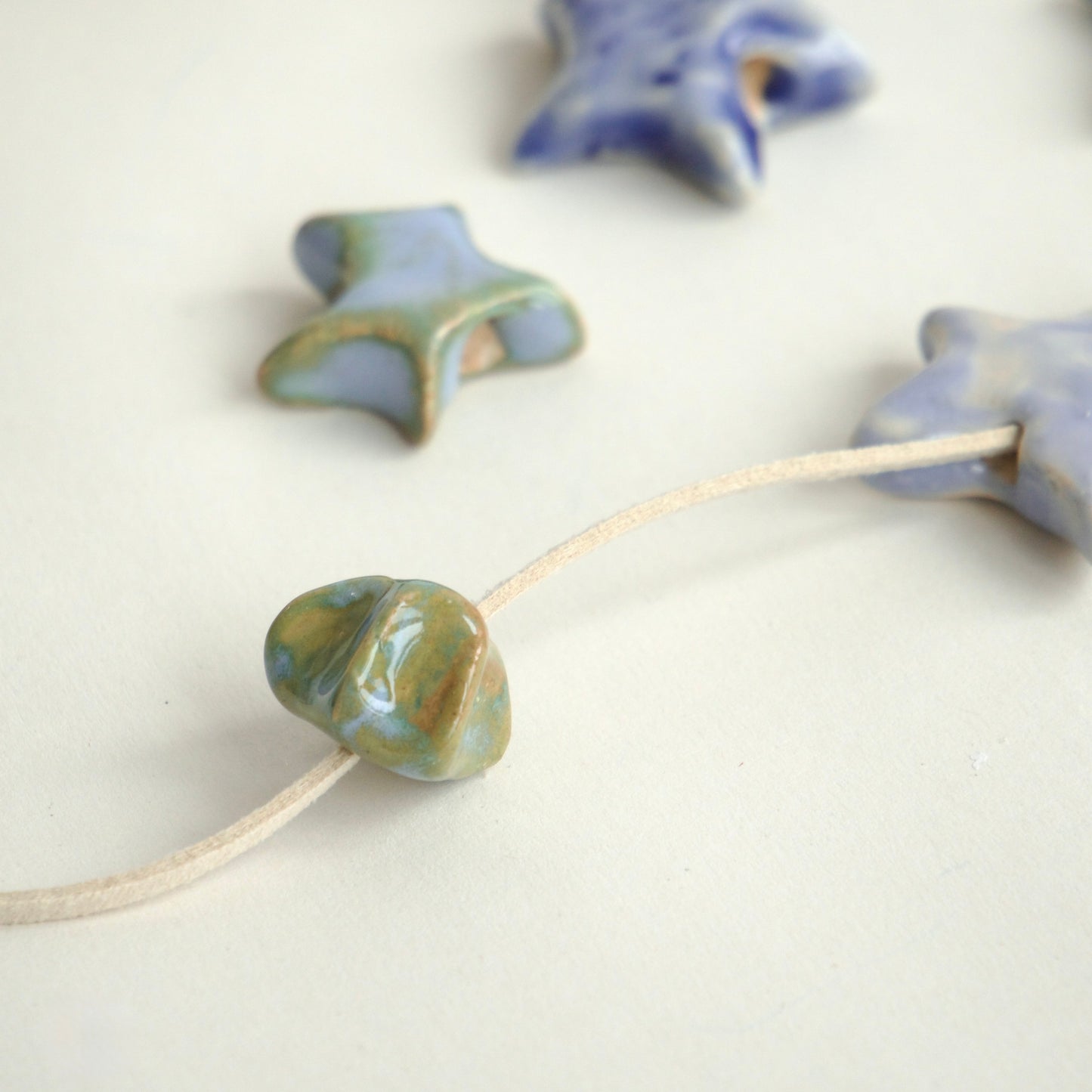 Charm ceramică handmade stea bleu pastel cu accente verzi.Produs unicat, ideal pentru coliere personalizate sau purtat singur.