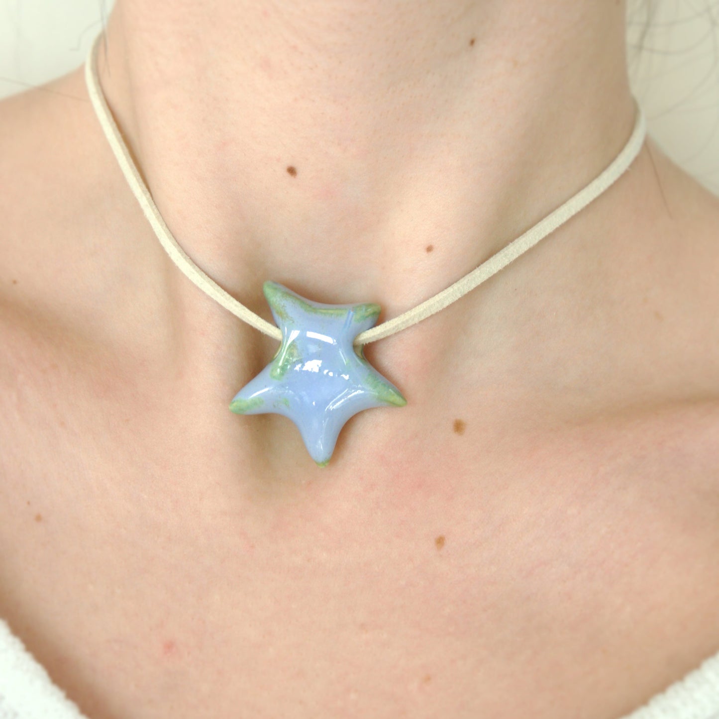 Colier cu pandantiv stea albastru lila cu reflexii verzi din ceramica prins pe snur din suede bej-ecluze studio.