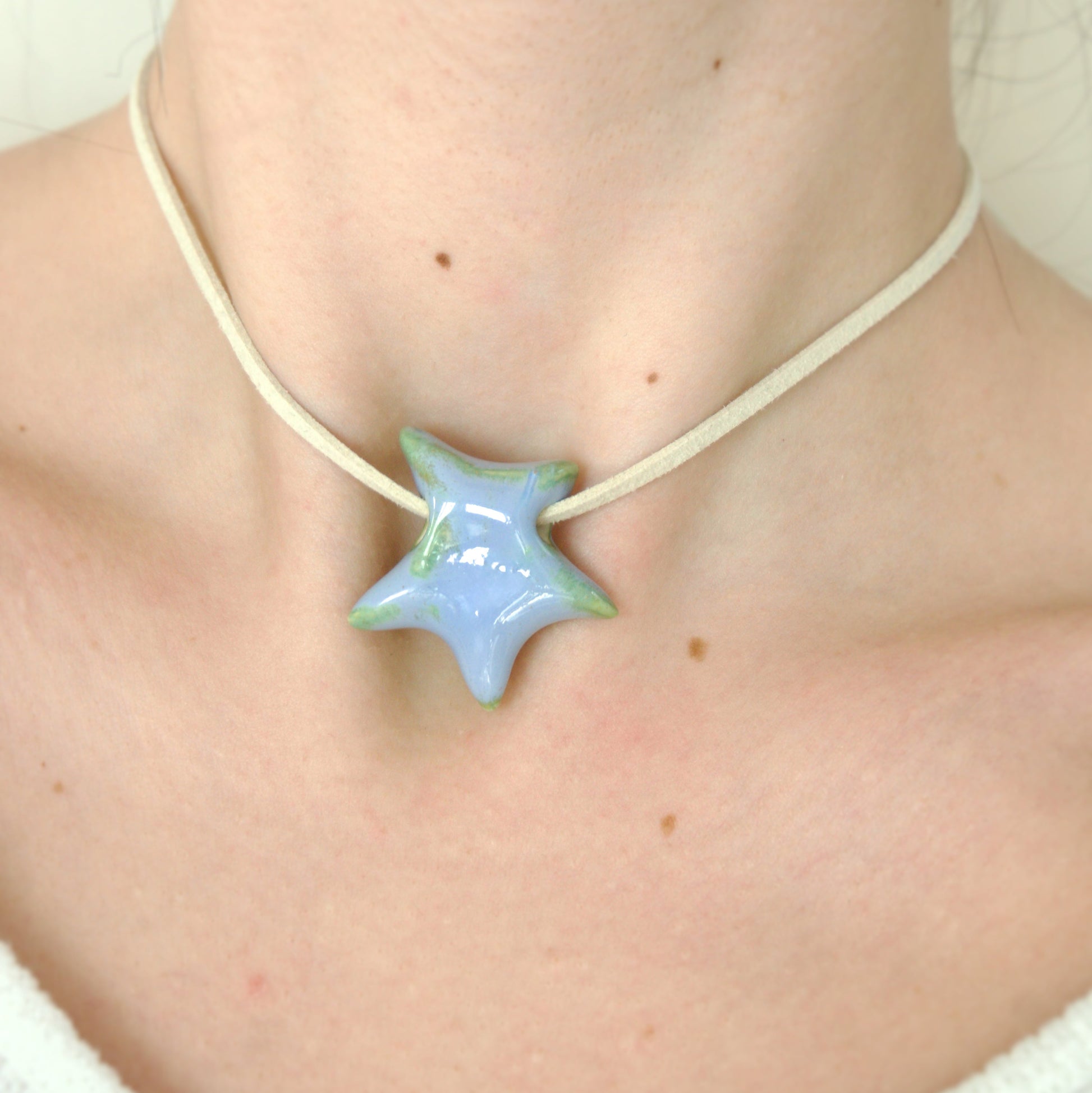 Colier cu pandantiv stea albastru lila cu reflexii verzi din ceramica prins pe snur din suede bej-ecluze studio.