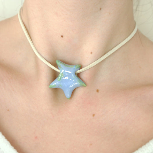 Colier cu pandantiv stea albastru lila cu reflexii verzi din ceramica prins pe snur din suede bej-ecluze studio.